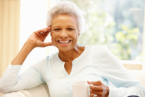 African american woman smiling on a couch while holding a coffee cup